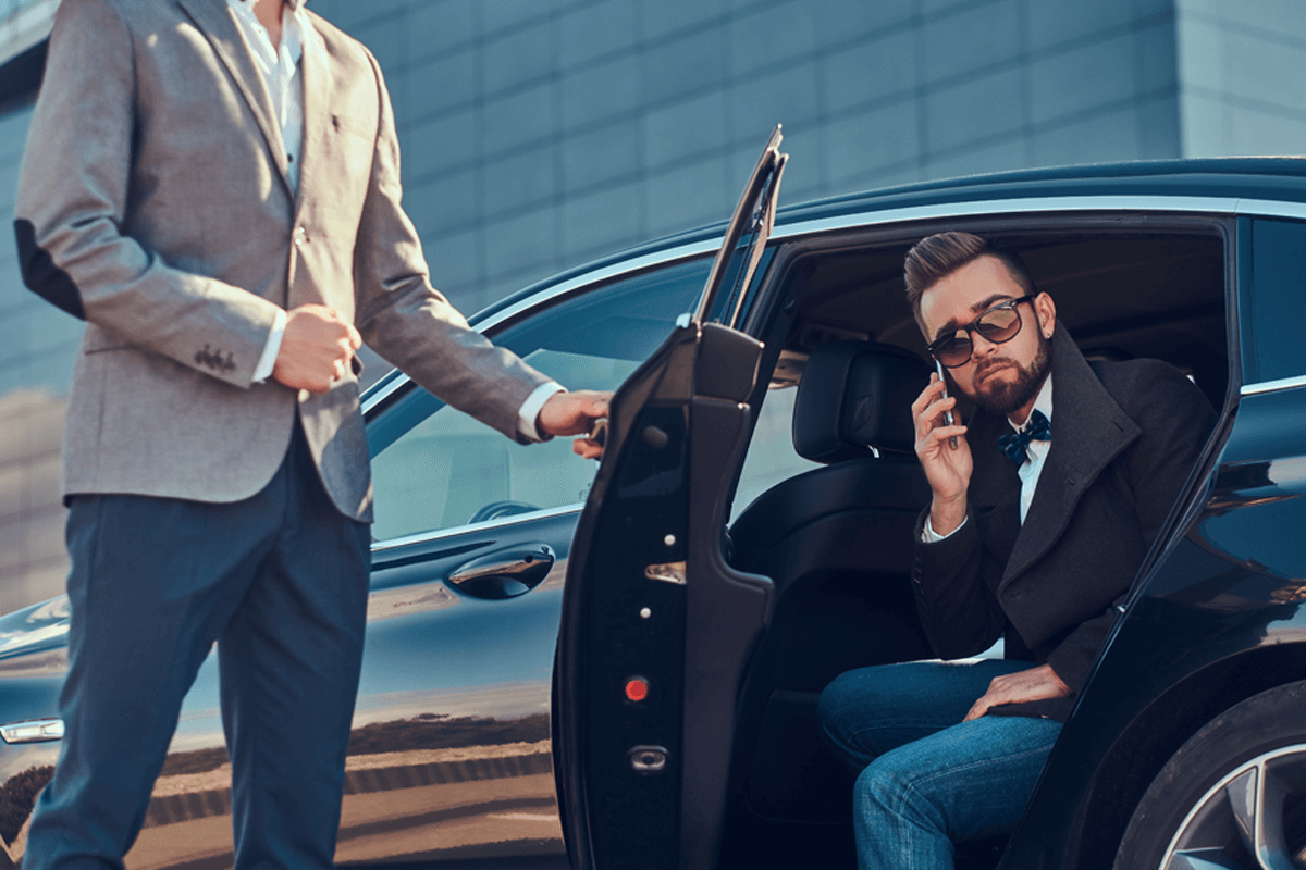 Businessman Is Talking By Mobile Phone While His Driver Is Opening Door For Him.jpg