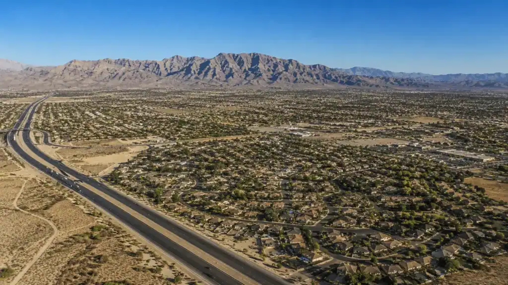 Aerial daytime view over Centennial Hills in northwest Las Vegas with suburban neighborhoods, the 215 Beltway, and the Sheep and Spring Mountain ranges in the background