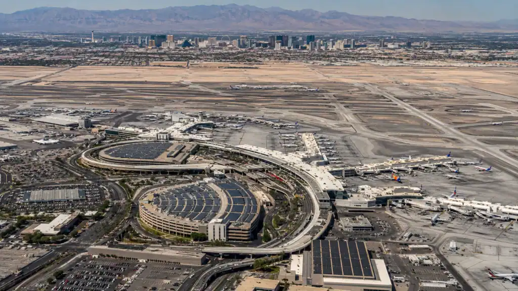 Aerial daytime view of Harry Reid International Airport Las Vegas showing the full campus with terminals runways and aircraft with the Las Vegas Strip skyline 3 miles to the north