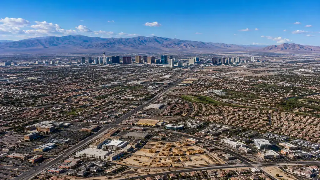 Aerial daytime view of the Las Vegas Valley showing residential suburbs in all directions from the Strip corridor toward mountain ranges representing the population and real estate statistics of the Las Vegas metropolitan area