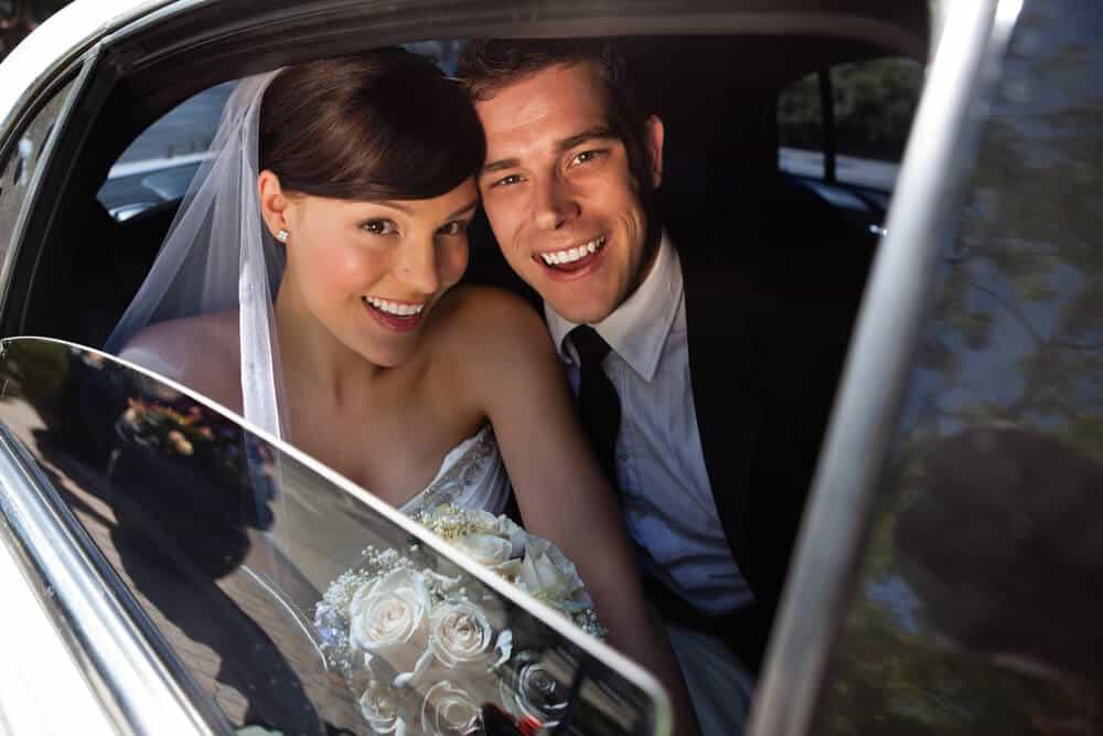 Happy newlywed couple in a chauffeured luxury car in Las Vegas - Personal Sedan Services