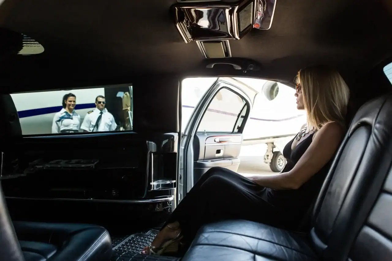 Personal Sedan Services chauffeur in a black suit meeting a passenger with a name sign at Harry Reid International Airport Zero Level