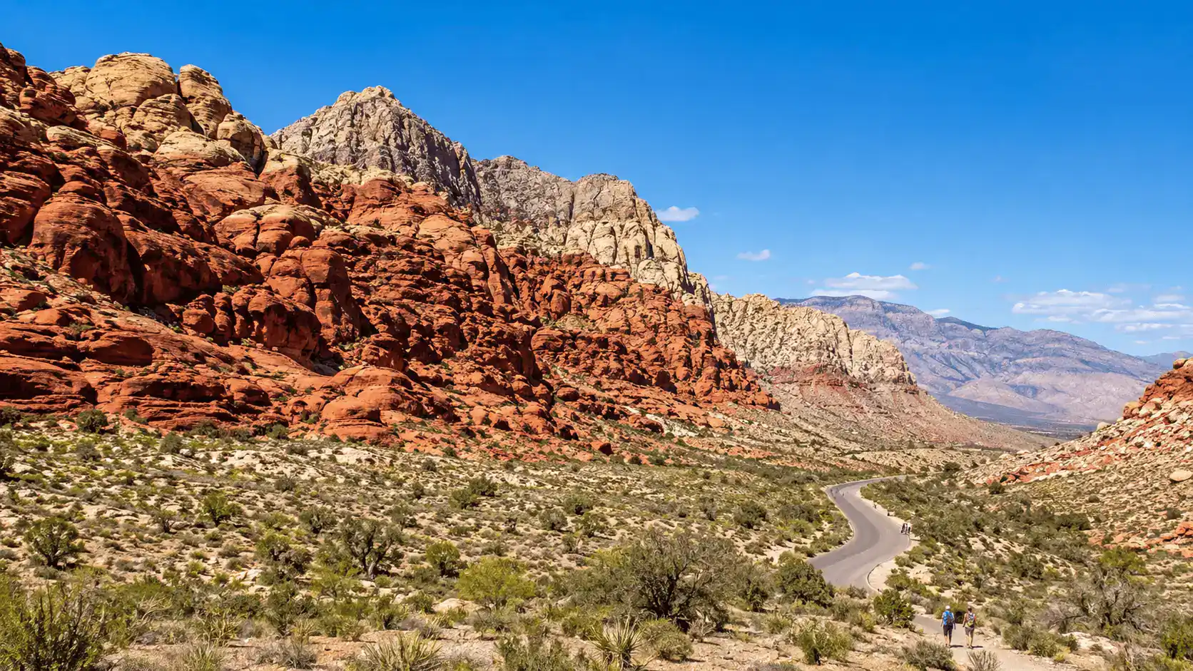 The red sandstone cliffs of Red Rock Canyon National Conservation Area just west of Summerlin with the scenic drive and hikers under a blue sky