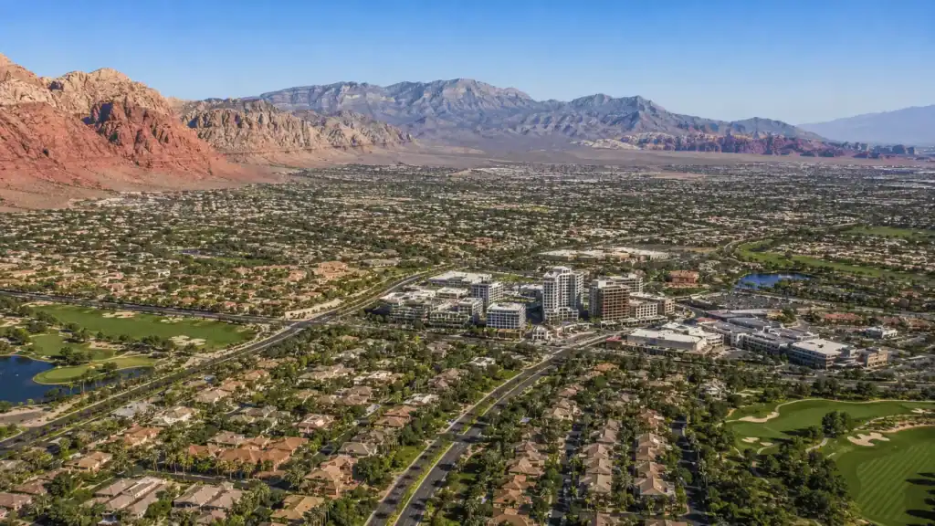 Aerial daytime view over Summerlin in west Las Vegas with master-planned neighborhoods, golf courses, and Downtown Summerlin against the red cliffs of Red Rock Canyon