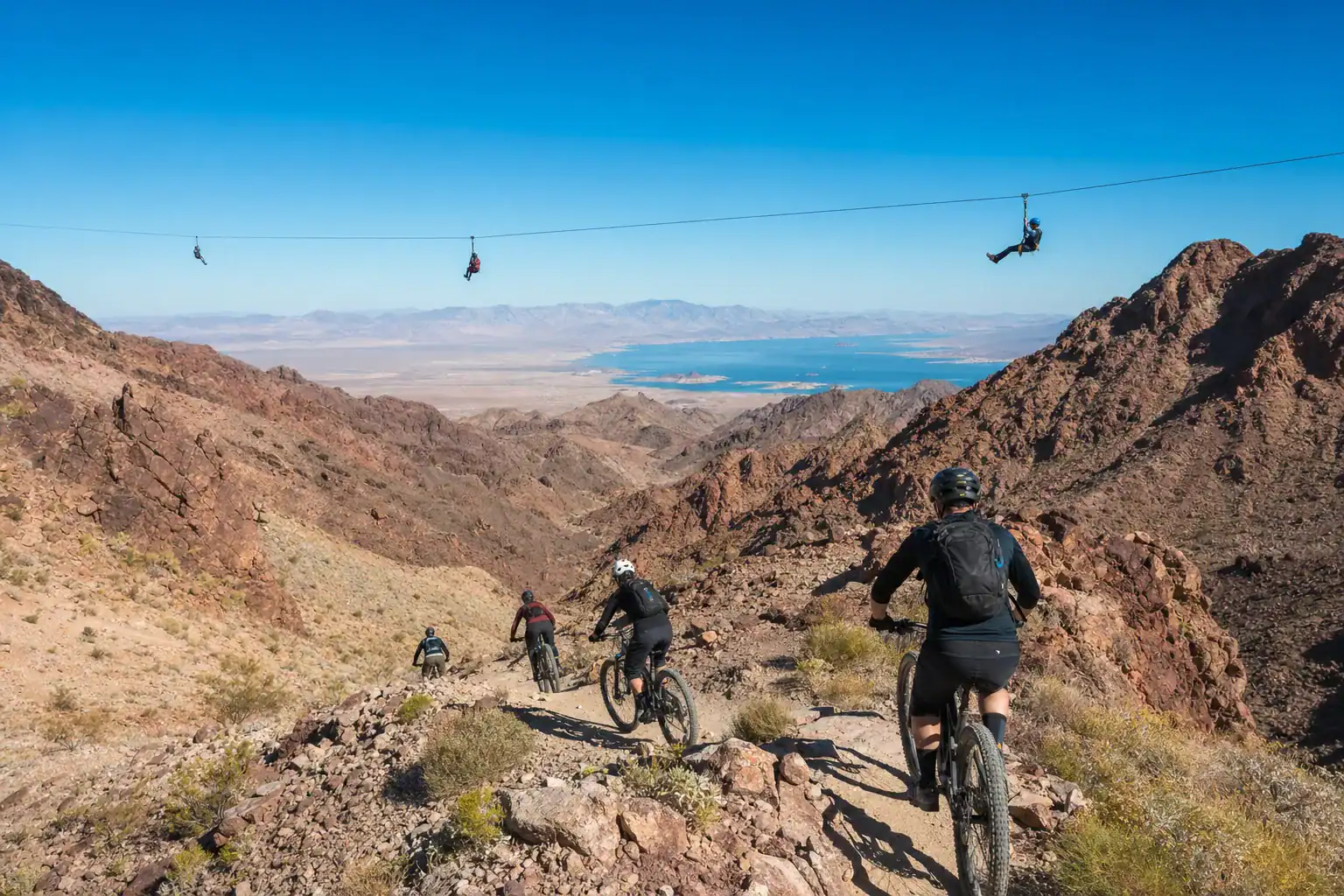 Mountain bikers and zipline riders at Bootleg Canyon near Boulder City Nevada with desert mountains and Lake Mead in the distance
