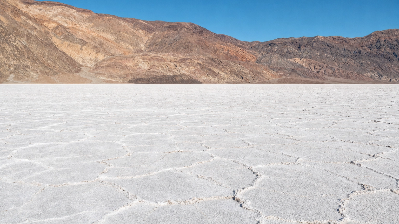 White salt flats of Badwater Basin stretching to golden mountains in Death Valley National Park near Las Vegas