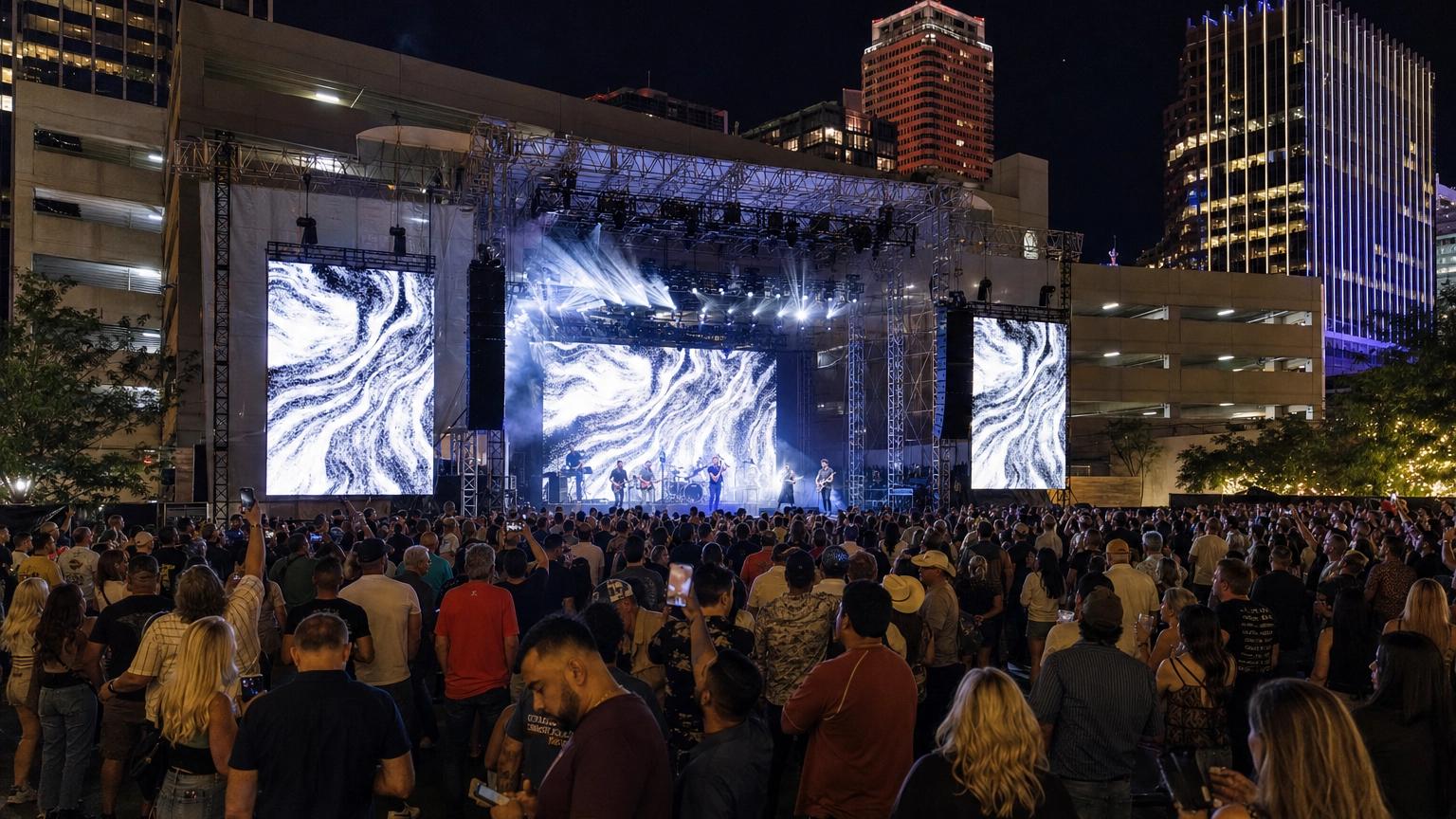 Open-air downtown Las Vegas concert with a lit stage and crowd framed by city buildings