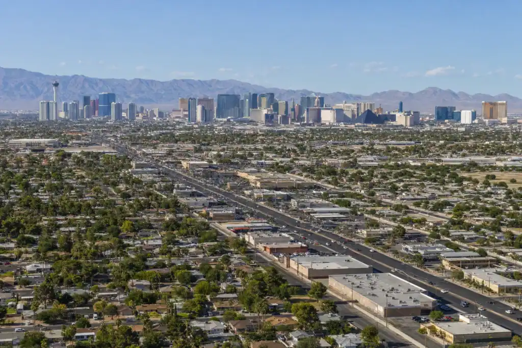 Aerial view of Las Vegas with a distant skyline of tall hotels and the mountains beyond.