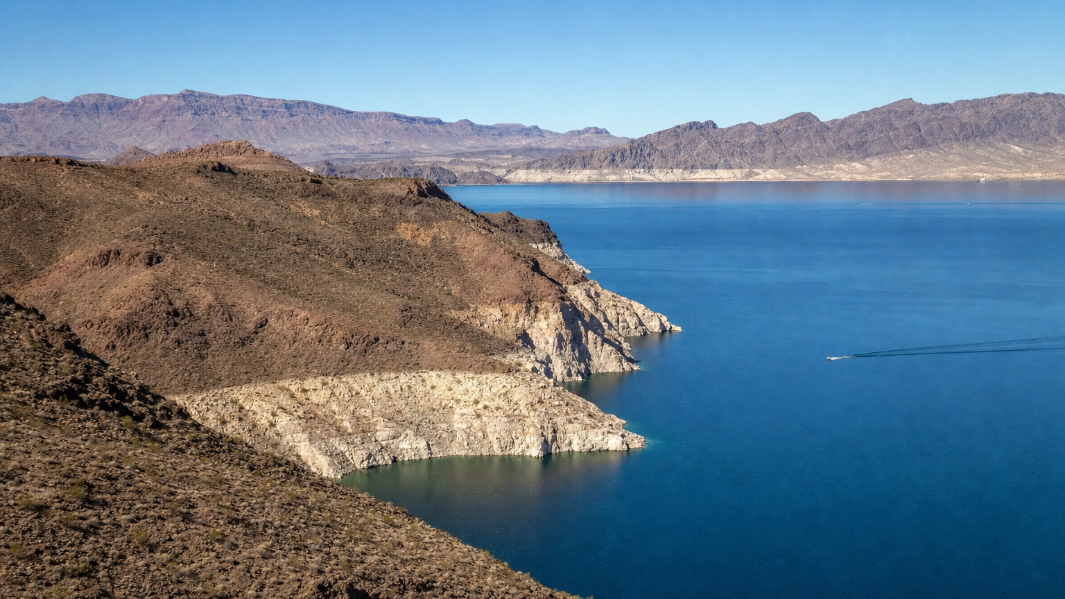 Bright blue Lake Mead reservoir water against tan desert mountains at Lake Mead National Recreation Area near Las Vegas