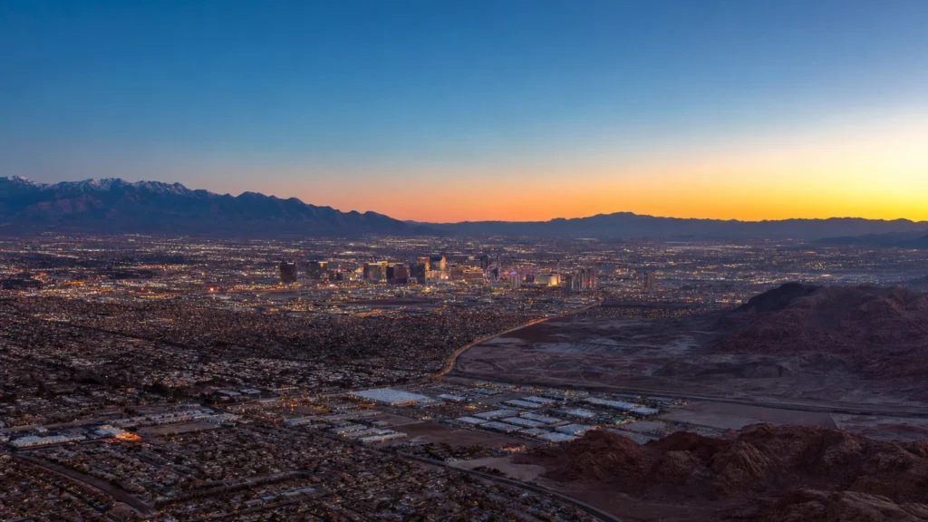 Aerial view of Las Vegas glowing in its Mojave Desert valley, ringed by mountains at dusk