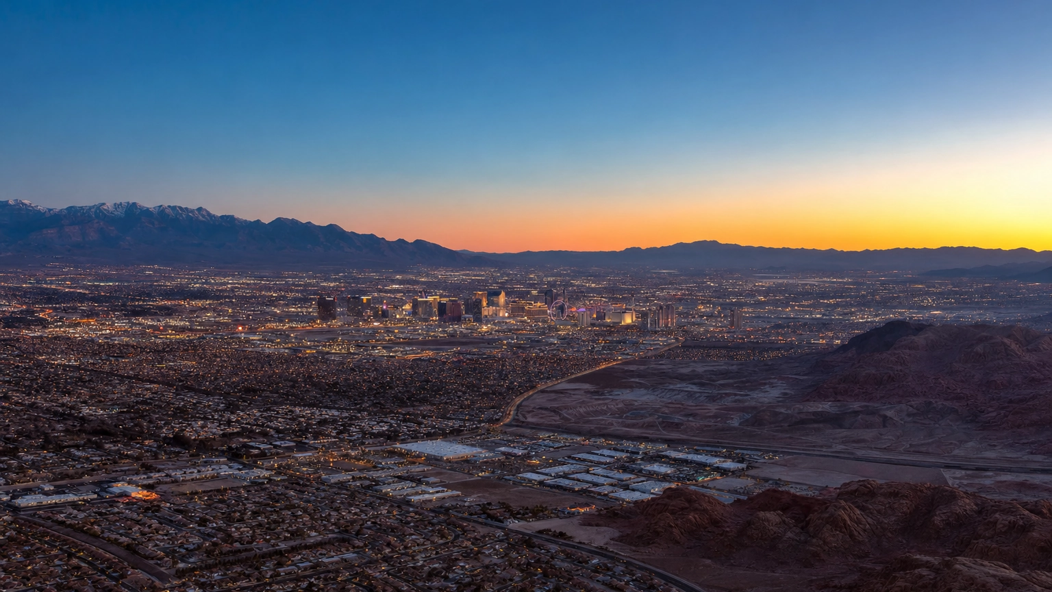 Aerial view of Las Vegas glowing in its Mojave Desert valley, ringed by mountains at dusk