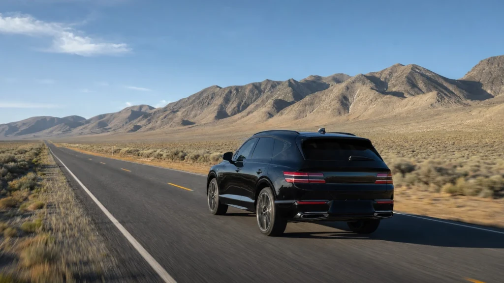 Black luxury SUV on an open two-lane desert highway in Nevada heading north toward Reno under a clear sky