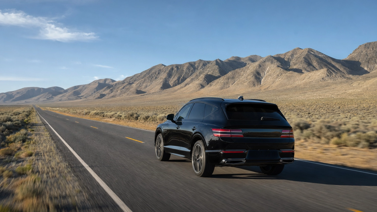 Black luxury SUV on an open two-lane desert highway in Nevada heading north toward Reno under a clear sky