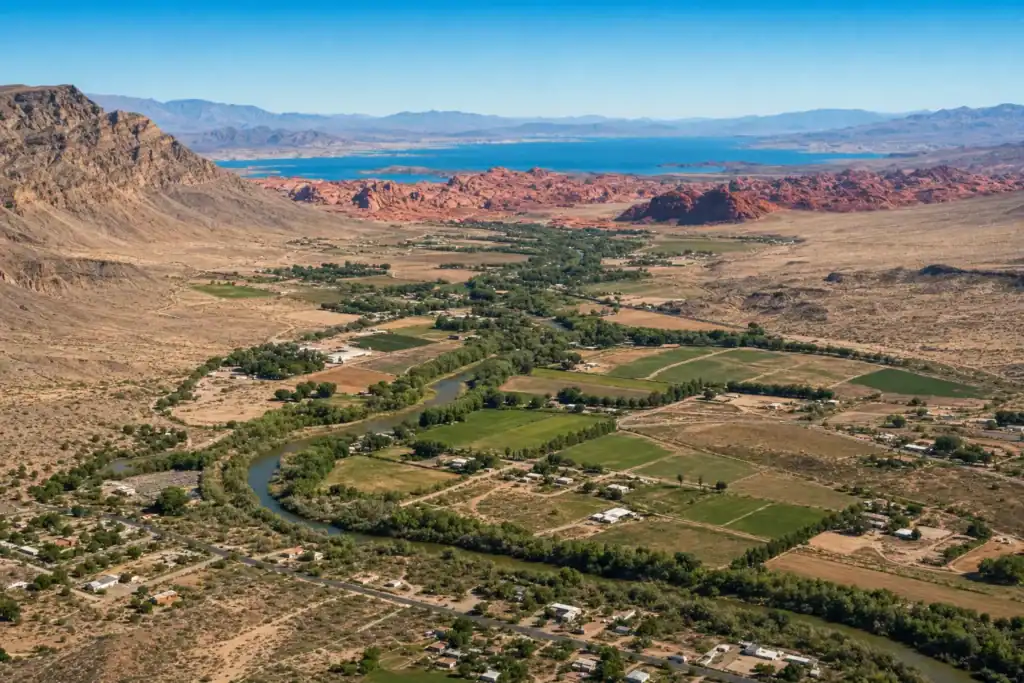 Aerial view over Moapa Valley Nevada showing green farmland along the Muddy River with red sandstone mesas, Valley of Fire, and Lake Mead beyond
