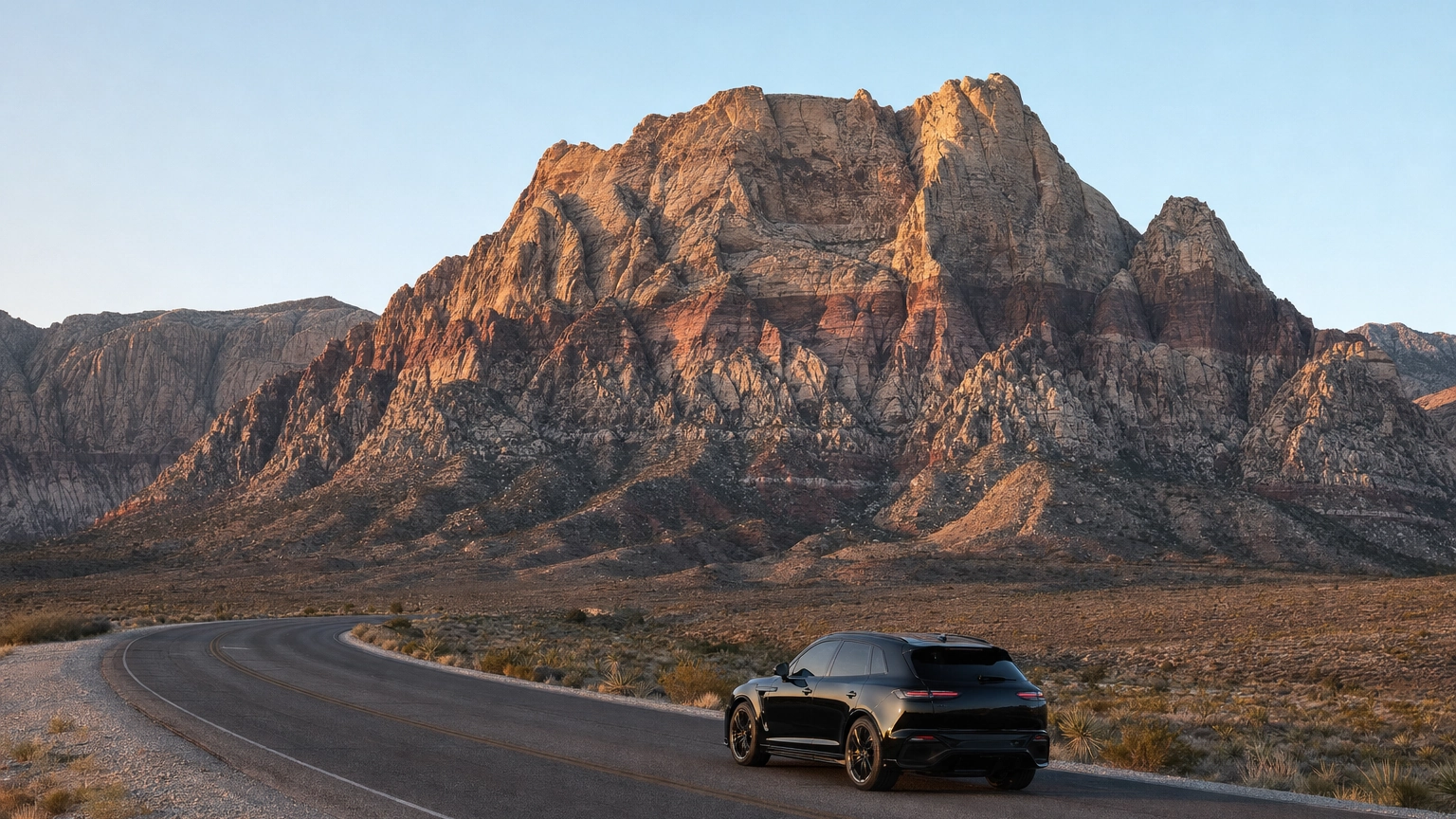 Black luxury SUV on the Red Rock Canyon scenic loop road with red sandstone cliffs west of Las Vegas